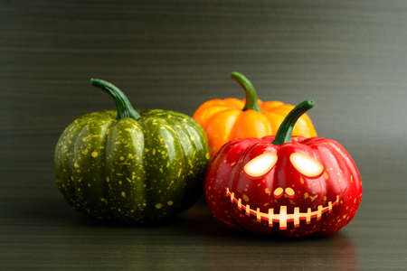 Three Halloween pumpkin with scary face on a dark green backgroundの写真素材