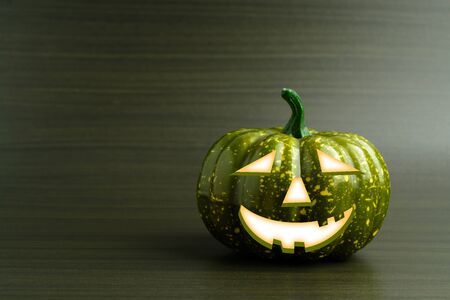 Three Halloween pumpkin with scary face on a dark green backgroundの写真素材