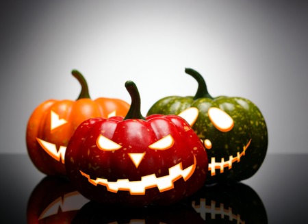 Three Halloween pumpkin with scary face on a gradient backgroundの写真素材