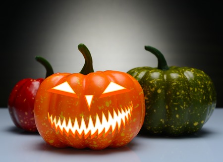 Three Halloween pumpkin with scary face on a gradient backgroundの写真素材