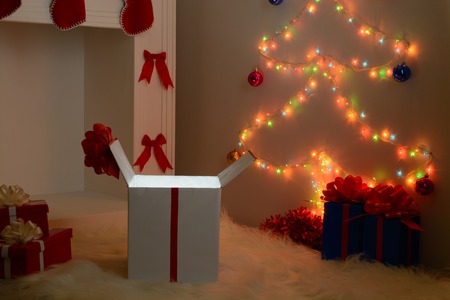 Christmas gifts near the white fireplace and decorated fir-treeの写真素材