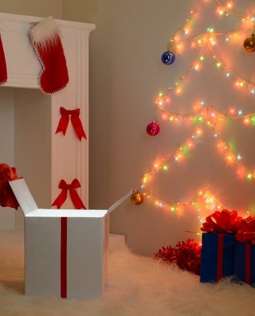 Christmas gifts near the white fireplace and decorated fir-treeの写真素材