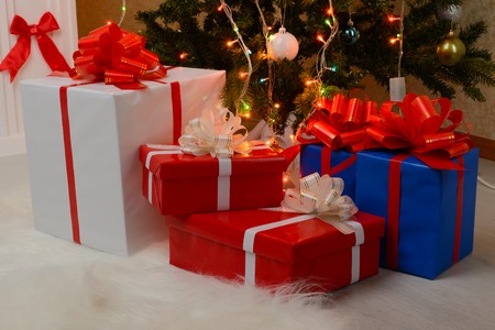 Christmas gifts near the white fireplace and decorated fir-treeの写真素材