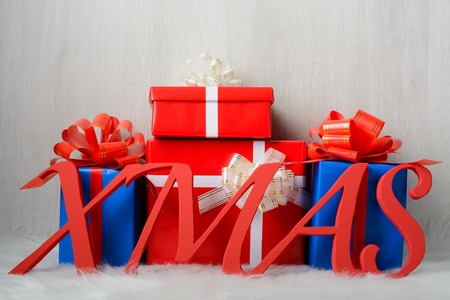 Word XMAS and Christmas gifts on a white carpet and a wooden backgroundの写真素材