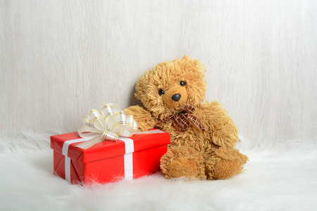 Teddy bear sitting on a white carpet with giftsの写真素材