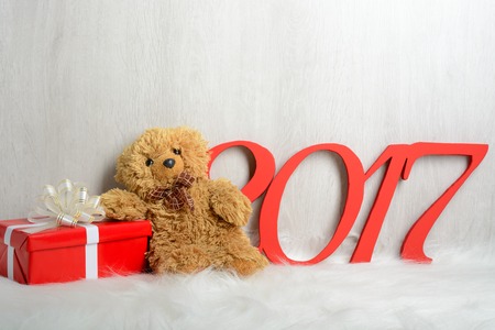 Teddy bear sitting on a white carpet with giftsの写真素材