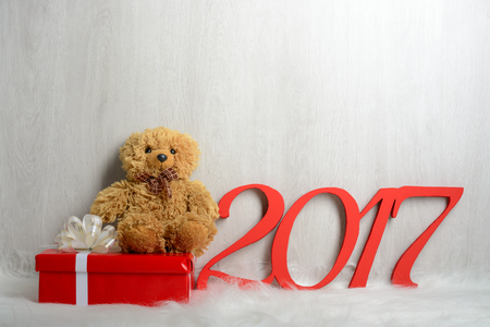 Teddy bear sitting on a white carpet with giftsの写真素材