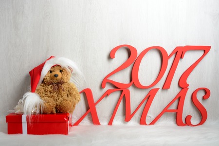 Teddy bear in santa hat with presents sitting on a white carpetの写真素材