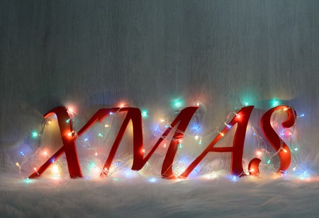 Inscription with Christmas garlands on fire on a white fur rugの写真素材