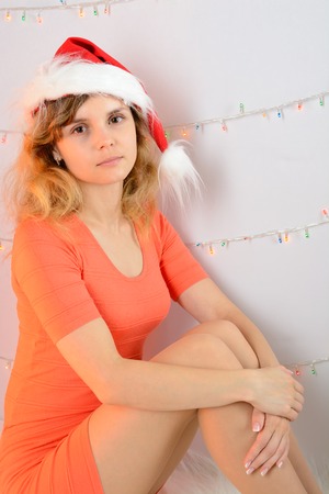 Young girl sitting in santa hat in orange dressの写真素材