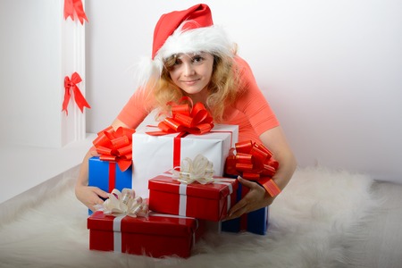 Girl in santa hat sitting by the fireplace with a gift boxの写真素材
