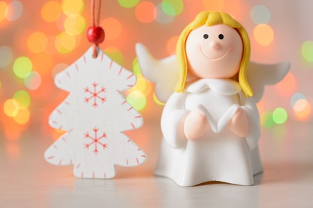 Toy angel with book and white spruce on a background of blurred lights garlandの写真素材