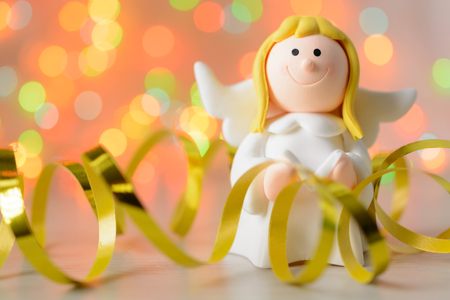 Toy angel with book in hand on the background of blurred lights garlandの写真素材