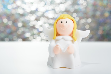 Toy angel with book in hand on the background of blurred lights garlandの写真素材