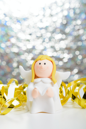Toy angel with book in hand on the background of blurred lights garlandの写真素材
