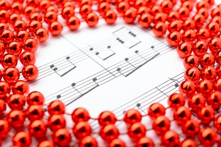 Christmas decorations red beads lie on sheets of notesの写真素材