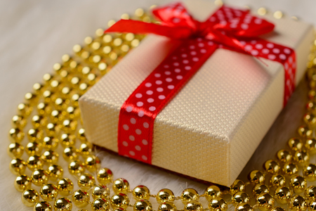 Gift box with red bow and gold beads on a fur rugの写真素材