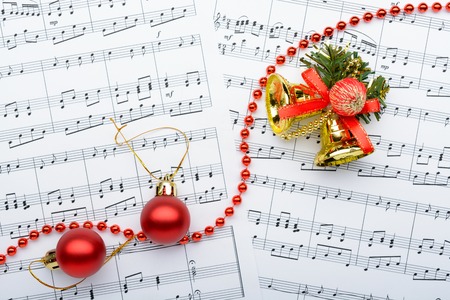 Christmas decoraChristmas decorations bells and balls lay on the sheets with notestions lying on notes sheetの写真素材