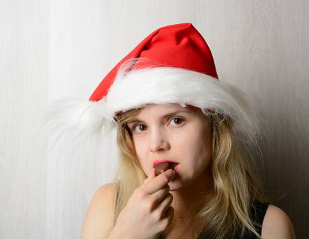 Girl in santa hat biting a chocolateの写真素材