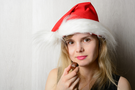 Girl in santa hat holding a chocolate candyの写真素材