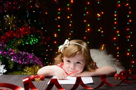 Little girl with red pencil writes a letter to Santa Clausの写真素材