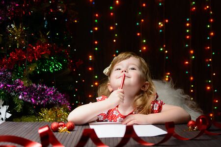 Little girl with red pencil writes a letter to Santa Clausの写真素材