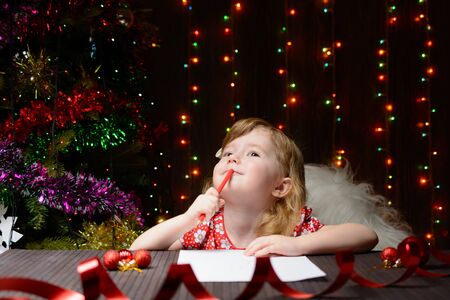 Little girl with red pencil writes a letter to Santa Clausの写真素材