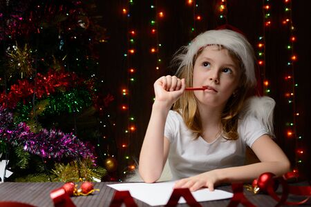 Little girl with red pencil writes a letter to Santa Clausの写真素材
