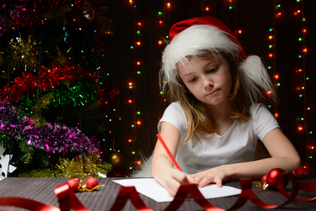 Little girl with red pencil writes a letter to Santa Clausの写真素材