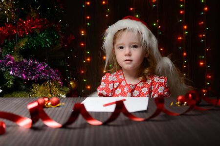Little girl with red pencil writes a letter to Santa Clausの写真素材