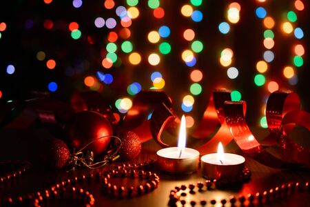 Burning candle on a table with Christmas decorations on a background garlandsの写真素材