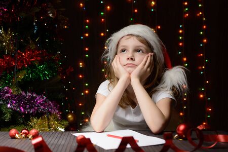 Little girl with red pencil writes a letter to Santa Clausの写真素材