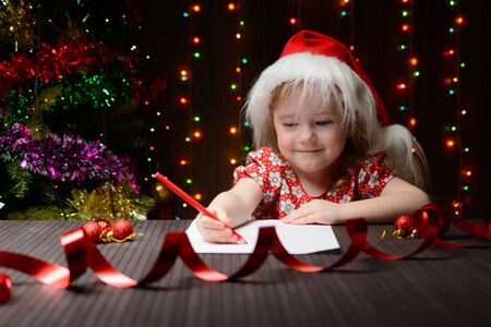 Little girl with red pencil writes a letter to Santa Clausの写真素材