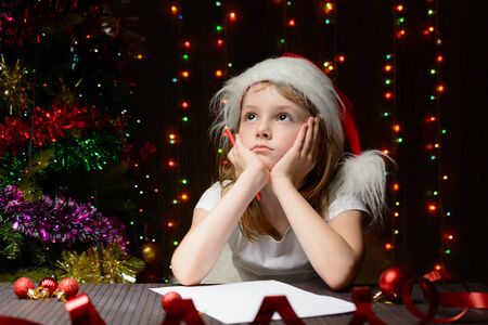 Little girl with red pencil writes a letter to Santa Clausの写真素材