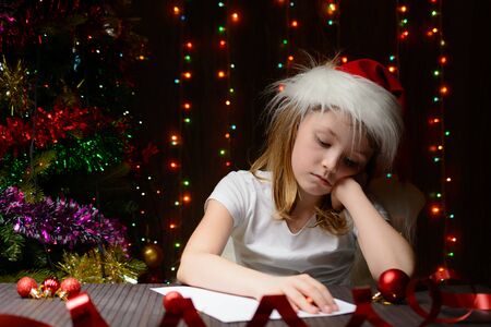 Little girl with red pencil writes a letter to Santa Clausの写真素材