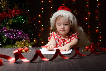 Little girl with red pencil writes a letter to Santa Clausの写真素材