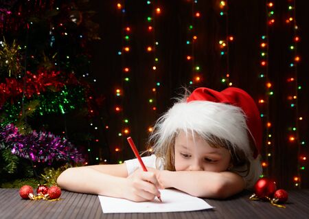 Little girl with red pencil writes a letter to Santa Clausの写真素材