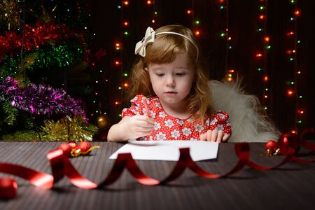Little girl with red pencil writes a letter to Santa Clausの写真素材
