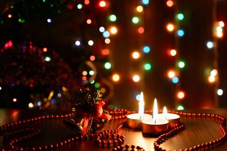 Burning candle on a table with Christmas decorations on a background garlandsの写真素材