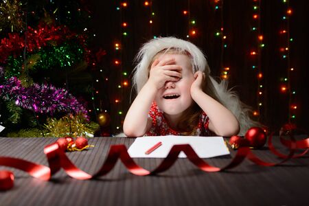 The girl wrote a letter to Santa Claus, and her hands over her eyesの写真素材