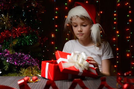 Girl in santa hat opening a red gift boxの写真素材