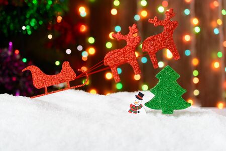 Christmas decoration sleigh and reindeer in the snow on a background garlandsの写真素材