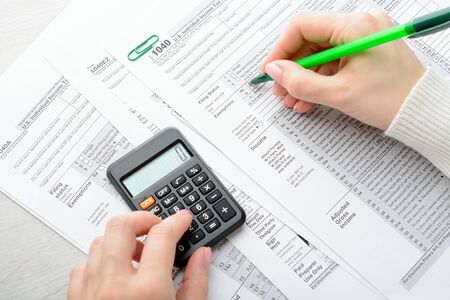 A woman sitting at a table and fills the tax formの写真素材