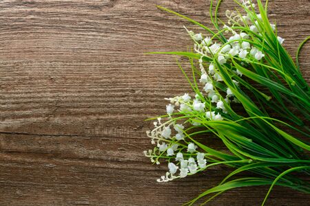 Bouquet of artificial lilies of the valley on a wooden tableの写真素材