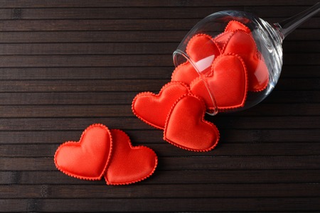 Red hearts in the glass and scattered on a table made of bamboo