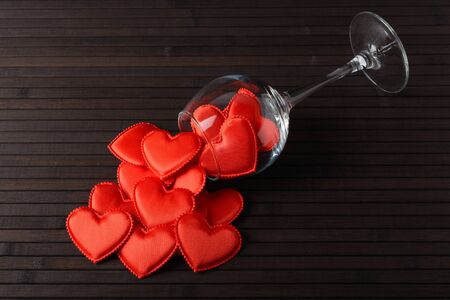 Red hearts in the glass and scattered on a table made of bambooの写真素材