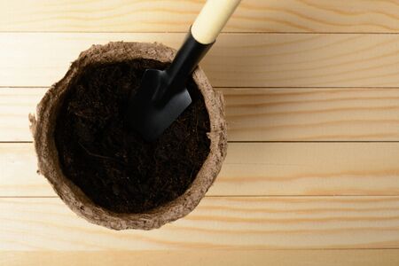 Peat pot with soil and a spade on a wooden tableの写真素材