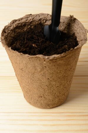Peat pot with soil and a spade on a wooden tableの写真素材