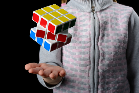 Almetyevsk City, Russia - February 7, 2017: a little girl holding a Rubik's cube on a black backgroundのeditorial素材