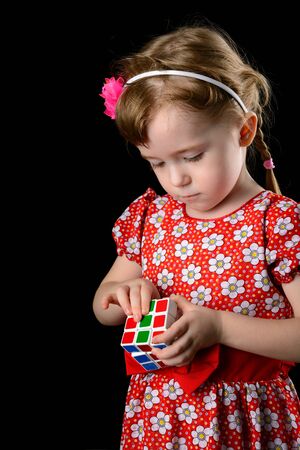 Almetyevsk City, Russia - February 7, 2017: a little girl holding a Rubik's cube on a black backgroundのeditorial素材
